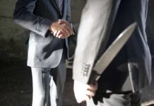 Two men shaking hands one holding hidden knife