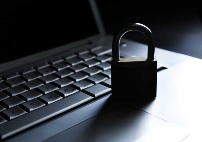 A padlock resting on a laptop keyboard in a dimly lit environment