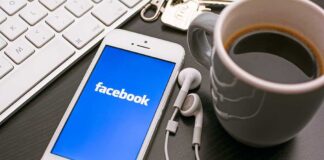 Smartphone displaying Facebook logo next to a cup of coffee and earphones